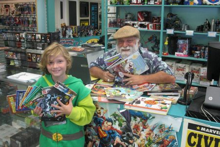 Joe holding up books with a young Atlantean